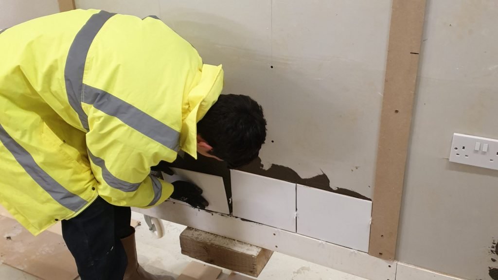 Male construction student tiling a wall