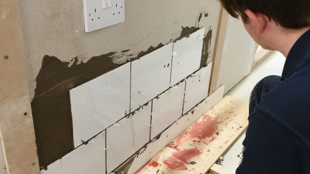 Close up of male construction student admiring tiling work