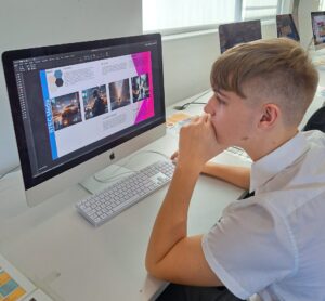 Male student looking at computer screen with his digital campaign design on show